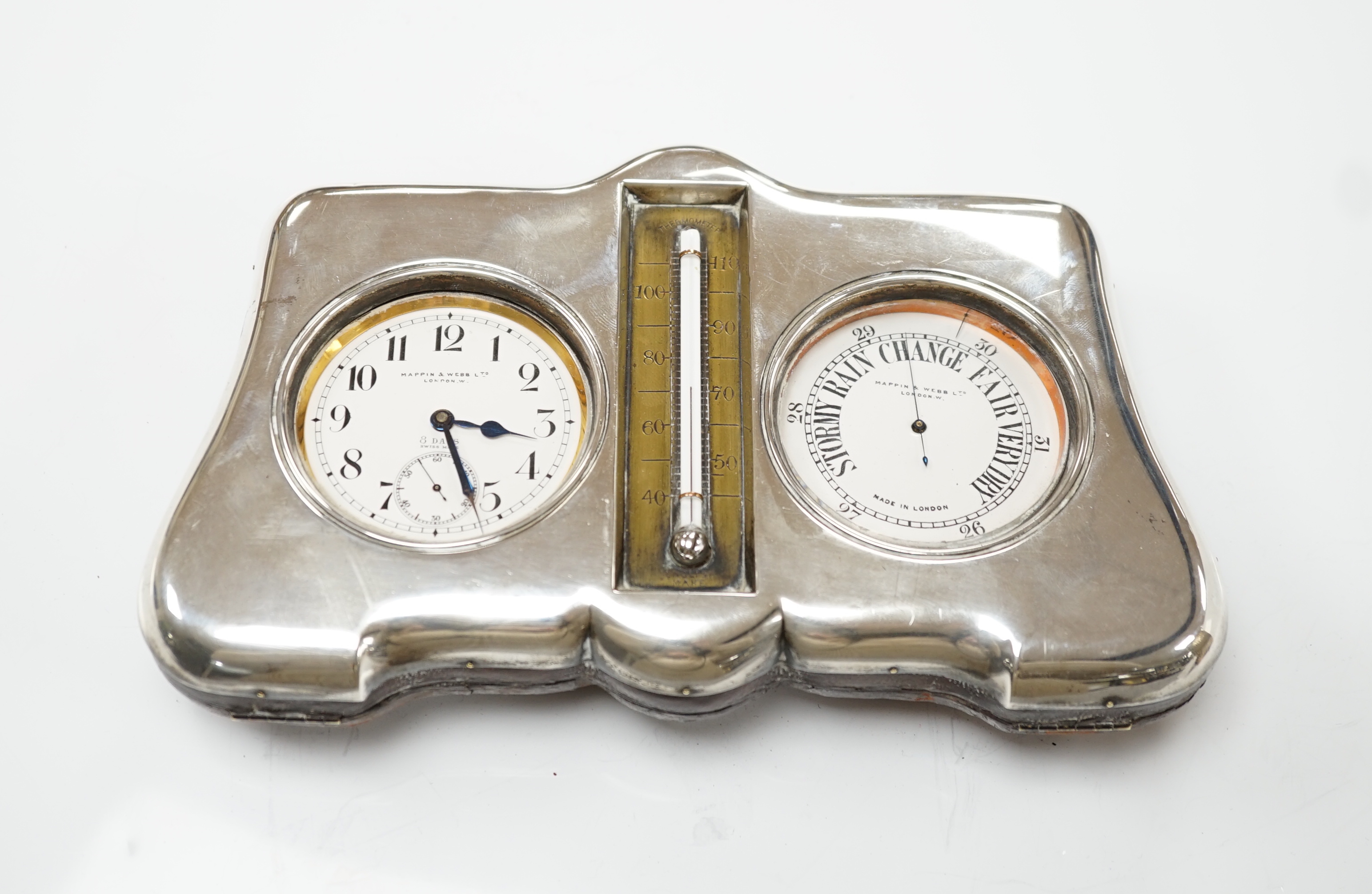 An Edwardian silver mounted leather clock/barometer desk stand, containing a pocket watch, retailed by Mappin & Webb, a similar barometer and a central thermometer, Henry Matthews, Birmingham, 1905, width 21.2cm.